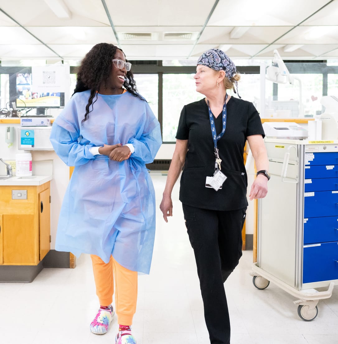 Two healthcare professionals walking and talking together in a brightly lit medical clinic.
