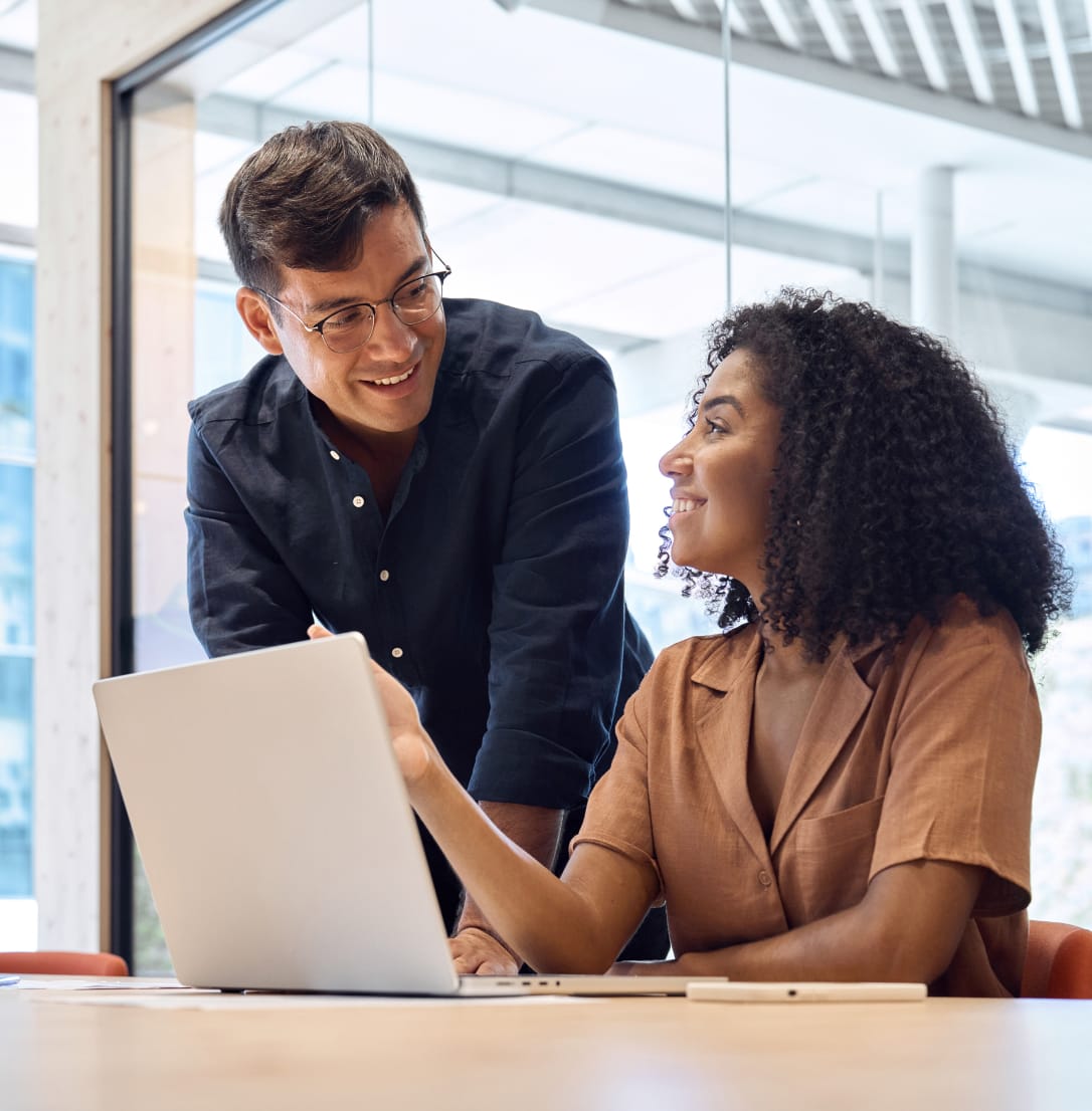 Two women sitting in front of laptop in office setting having discussion. 